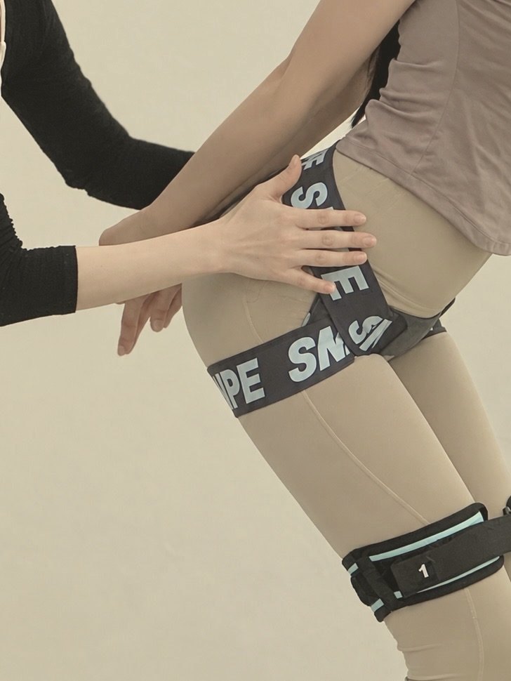 SNPE 밴드를 착용한 회원의 골반 위치를 손으로 잡아 주는 개인레슨